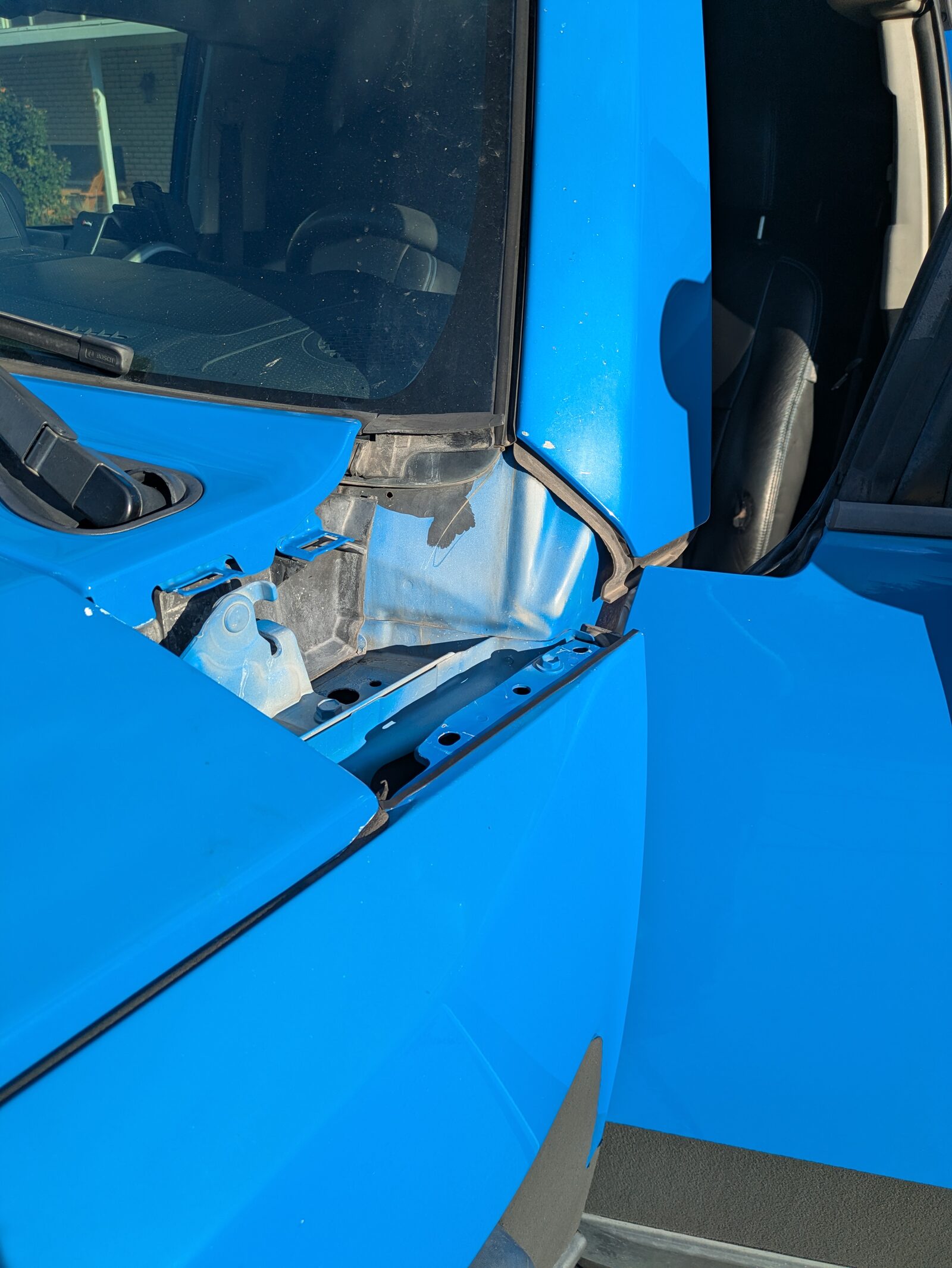 The hole the panel left behind: the hood hinge, mounting clips, and an unpainted outline on the A-pillar base